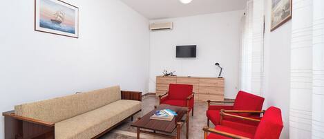 A living room with a sofa, a coffee table, and red chairs.