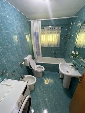 A bathroom with a toilet, bidet, bathtub, and sink. - Apartment Lucille (Kali)
