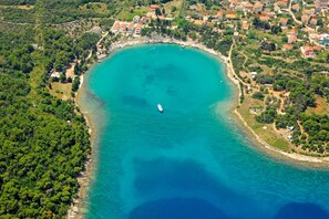 An aerial view of a coastal town with a narrow bay, surrounded by dense greenery and residential buildings with red roofs. - Apartment Lucille (Kali)