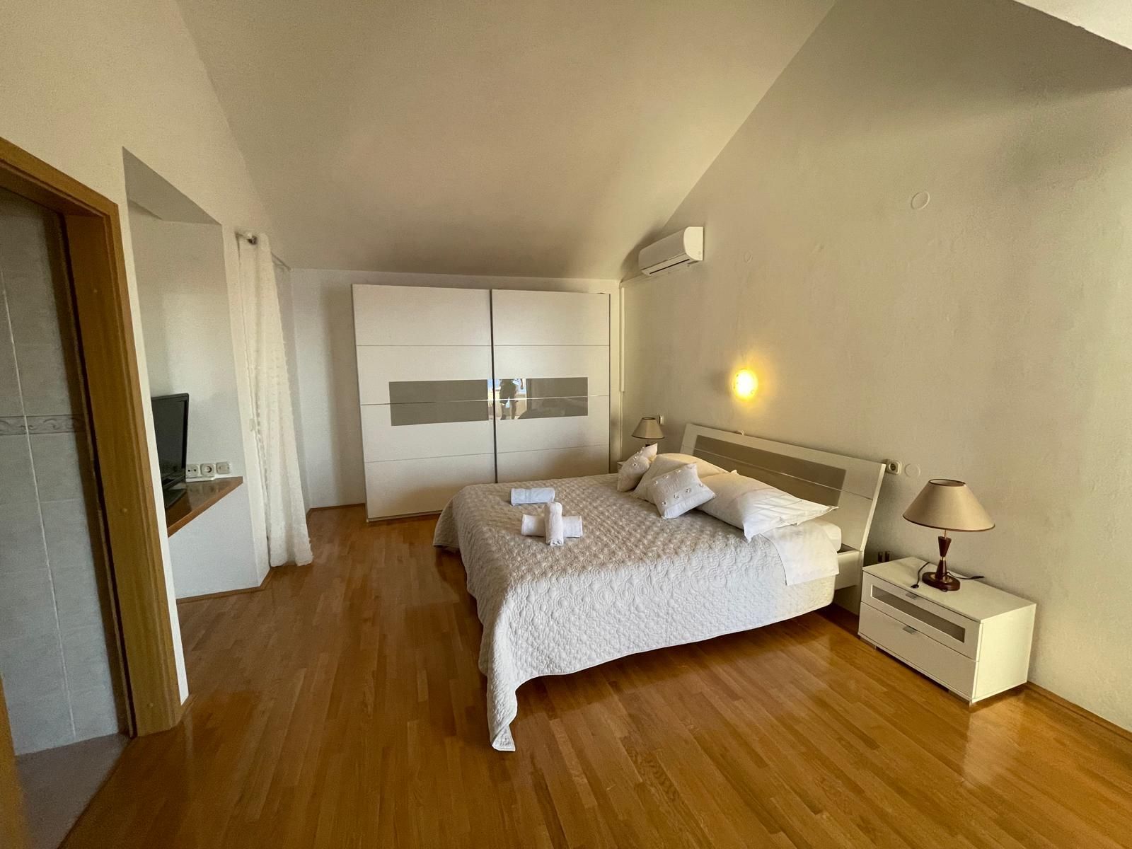 A bedroom with a bed, bedside tables, a wardrobe, and a TV.