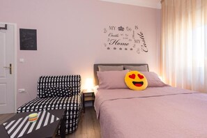 Ein Schlafzimmer mit Bett, Stuhl, Nachttisch und Wandbild.