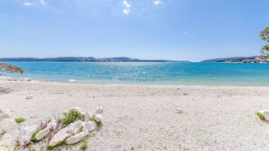 A beach with clear blue water, white sand, and distant hills. - Room Ela (Seget)
