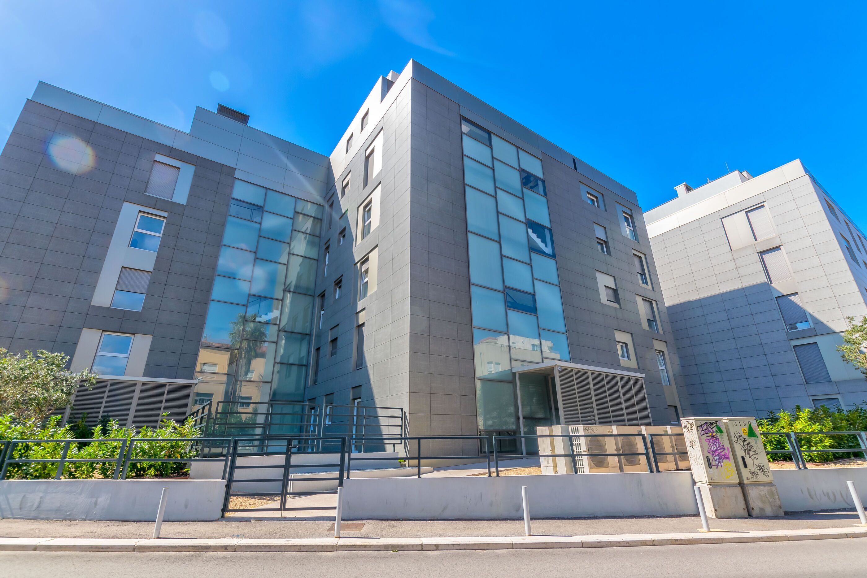Een modern gebouw met meerdere verdiepingen, grote ramen en een plat dak.