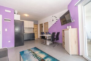 A modern kitchen with a built-in fridge, a dining area with a table and chairs, and a TV mounted on the wall. - Apartments Kristina (Benkovac)