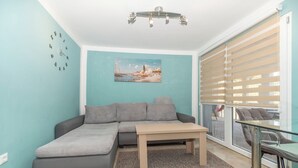 Ein Wohnzimmer mit Ecksofa, einem kleinen Tisch und einem Gemälde an der Wand.