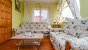 A cozy living room with a sofa, a coffee table, and a window with curtains. - Apartment Sweet (Marina)