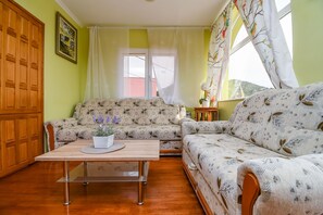 A cozy living room with a sofa, a coffee table, and a window with curtains. - Apartment Sweet (Marina)