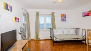 A room with a bed, a TV, a fan, and a window with curtains. - Apartments Mrvelj (Jelsa)