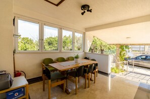 A conference room with a long table and chairs, large windows, and a view of greenery outside. - Apartments Mrvelj (Jelsa)