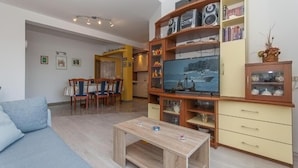 Un soggiorno con un divano, un tavolino, una TV e una libreria.