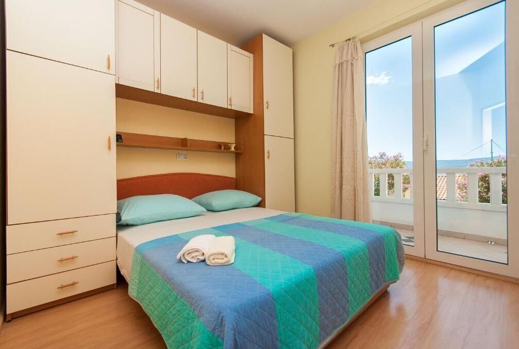 A bedroom with a bed, a wardrobe, and a balcony with a view.