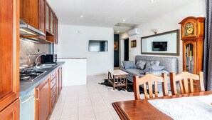 Een moderne keuken met houten kastjes, een inbouwfornuis en een eethoek met een houten tafel en stoelen.
