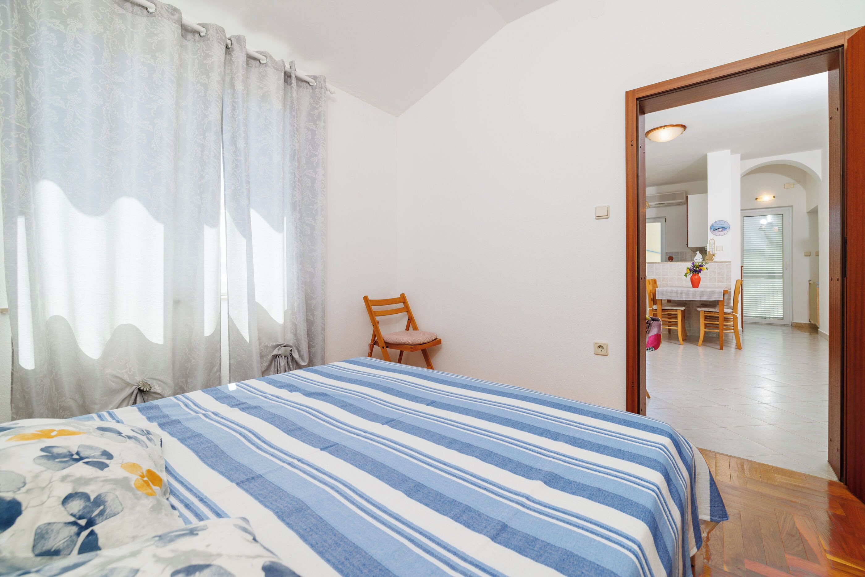 Un dormitorio con una cama, una silla y vista a un comedor.