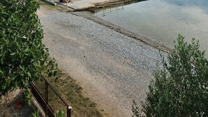Ein ruhiger See mit einem Steg, der sich ins Wasser erstreckt, umgeben von Bäumen und einem klaren Himmel.