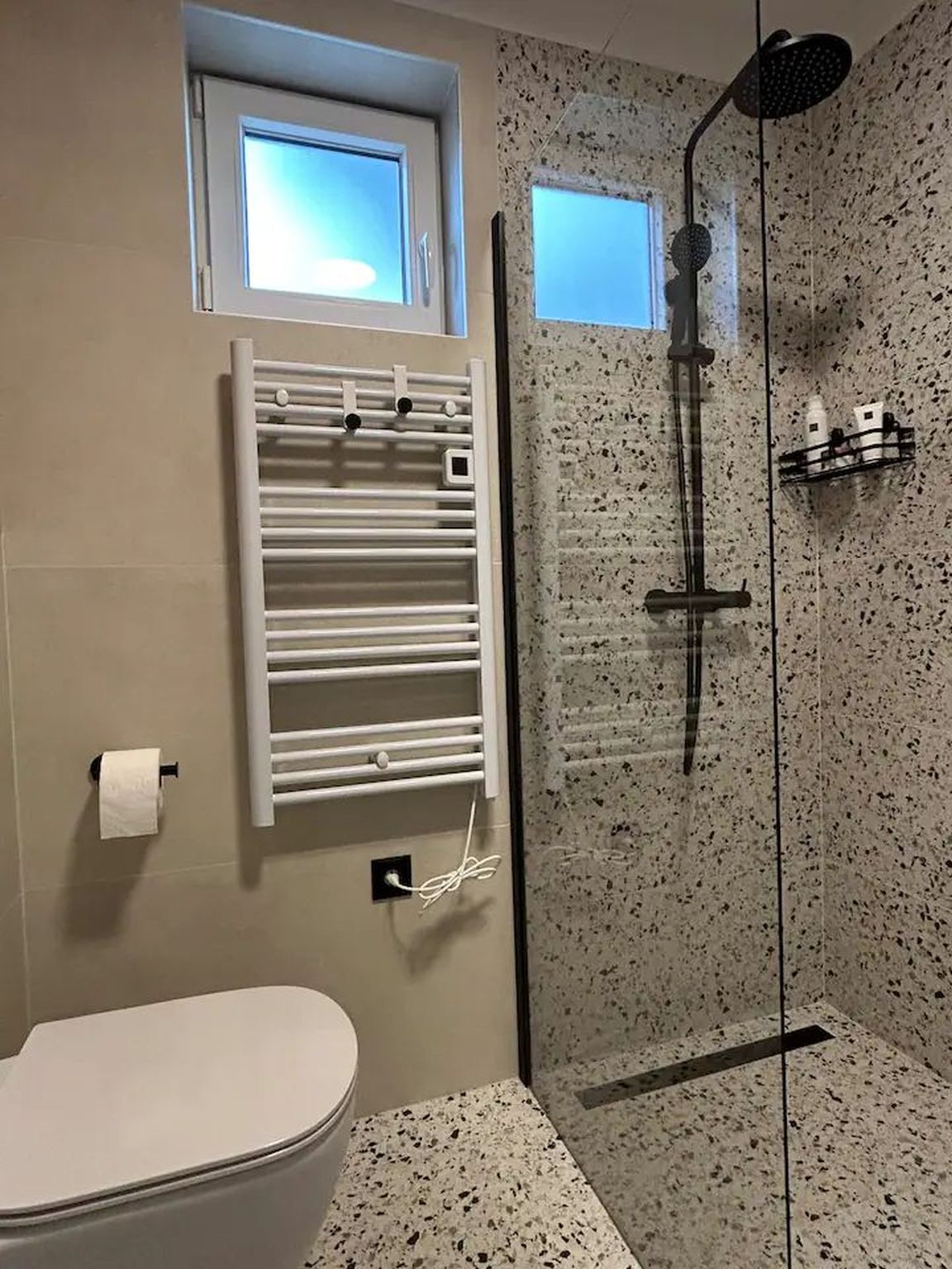 Ein Badezimmer mit Toilette, einer Duschkabine und einem Handtuchhalter.
