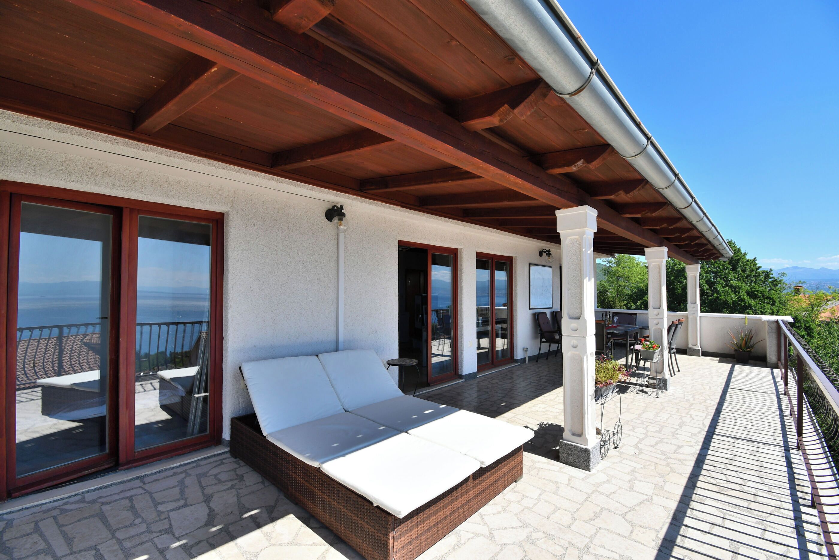 Un balcon avec un canapé en osier, un coin repas et une vue sur la mer.