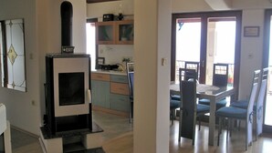 Cozinha moderna com fogão embutido, espaço de refeições com mesa e cadeiras, e vista para o exterior através de uma porta.
