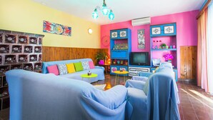 A living room with a sofa, chairs, a TV, and a decorative wall with shelves. - Apartment Colorful (Smokvica)