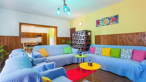 A living room with a sectional sofa, a small round table, and a bookshelf. - Apartment Colorful (Smokvica)