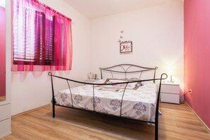 Una camera da letto con un letto, un comodino, un quadro appeso al muro e una finestra con tende.