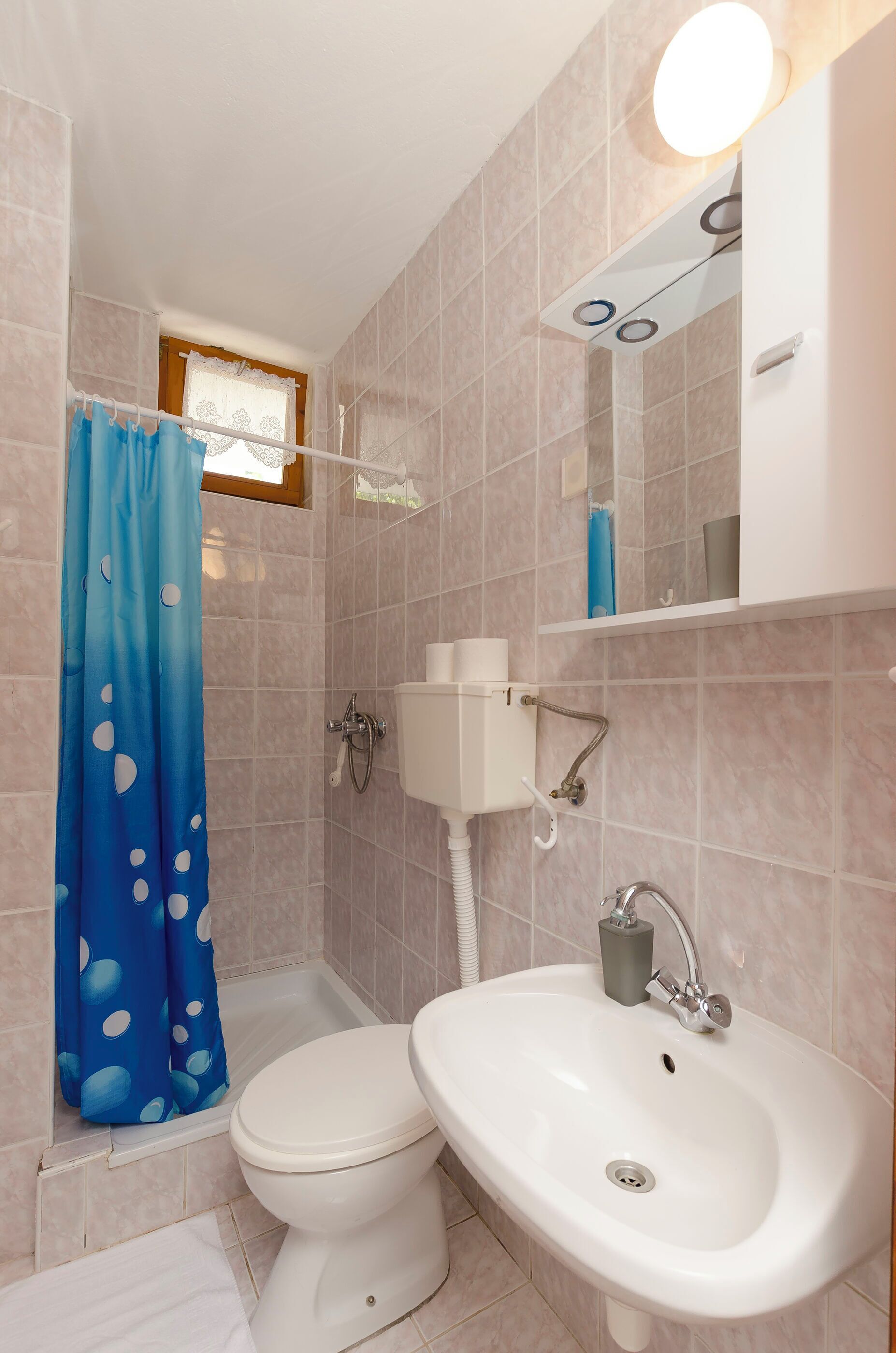 Un baño con inodoro, lavamanos, cortina de ducha y espejo.