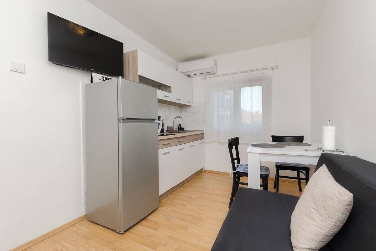 Una cocina compacta con refrigerador, estufa y comedor con mesa y sillas.