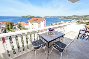 En balkon med bord og stole, der giver udsigt over kysten.