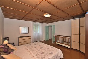 Ein Schlafzimmer mit Bett, Schminktisch und Babybett.