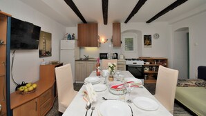 Un comedor con una mesa dispuesta para cuatro, armarios de madera, un microondas y una cocina al fondo.