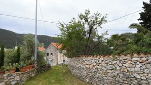 Un muro de piedra con un sendero de piedra que lleva a un edificio con techo de tejas.