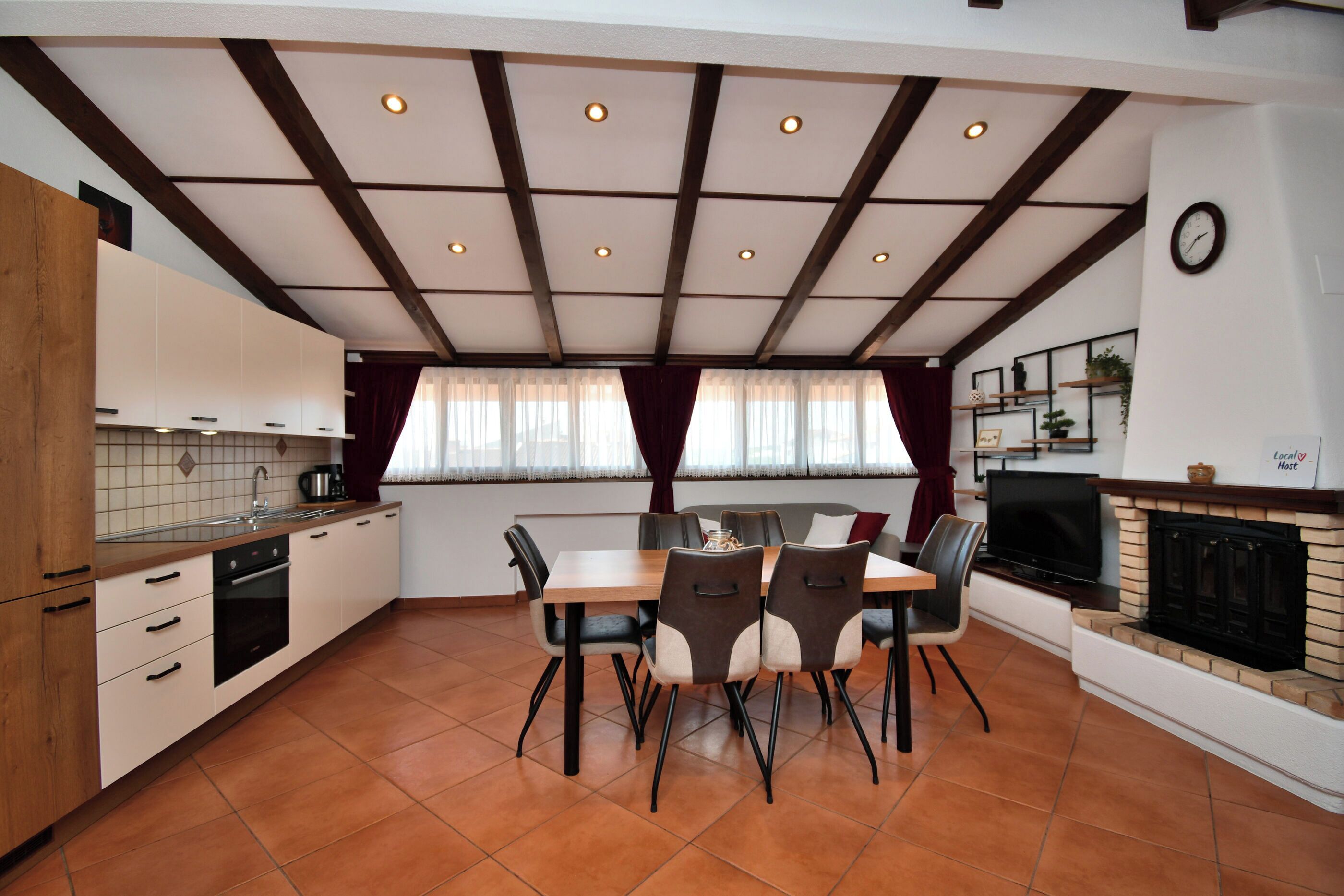 A modern kitchen with a dining area, featuring a tiled backsplash, wooden cabinets, and a built-in oven.