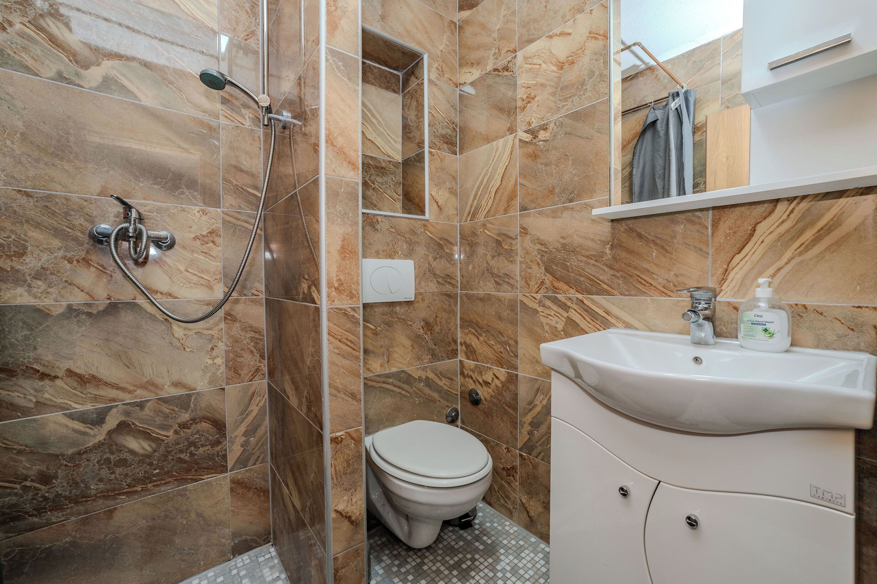 A bathroom with a shower, toilet, and sink.