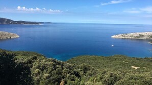 Eine Küstenlandschaft mit freiem Blick auf das Meer, Hügel und eine kleine Insel.