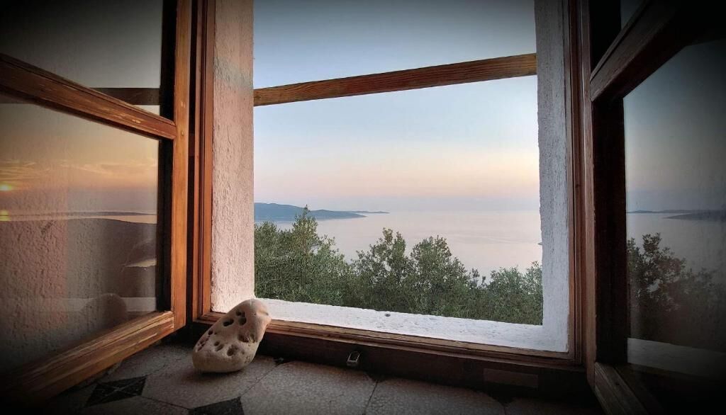 Quarto com uma grande janela com vista para um corpo de água e terras distantes.
