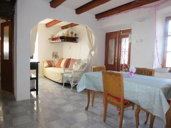 A dining area with a table set for four, a sofa, and a chair. - Apartments Rose (Mali Losinj)