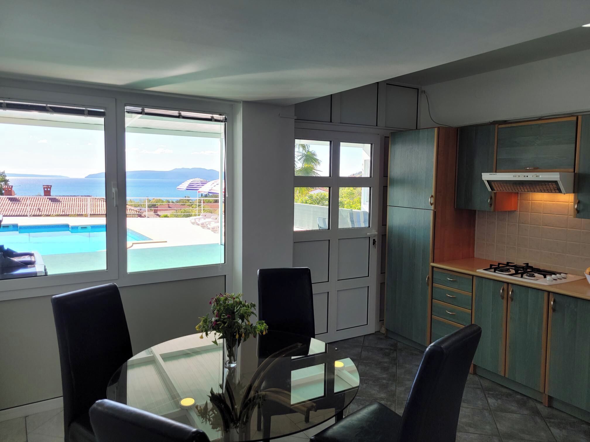 A modern kitchen with a view of a swimming pool and mountains.