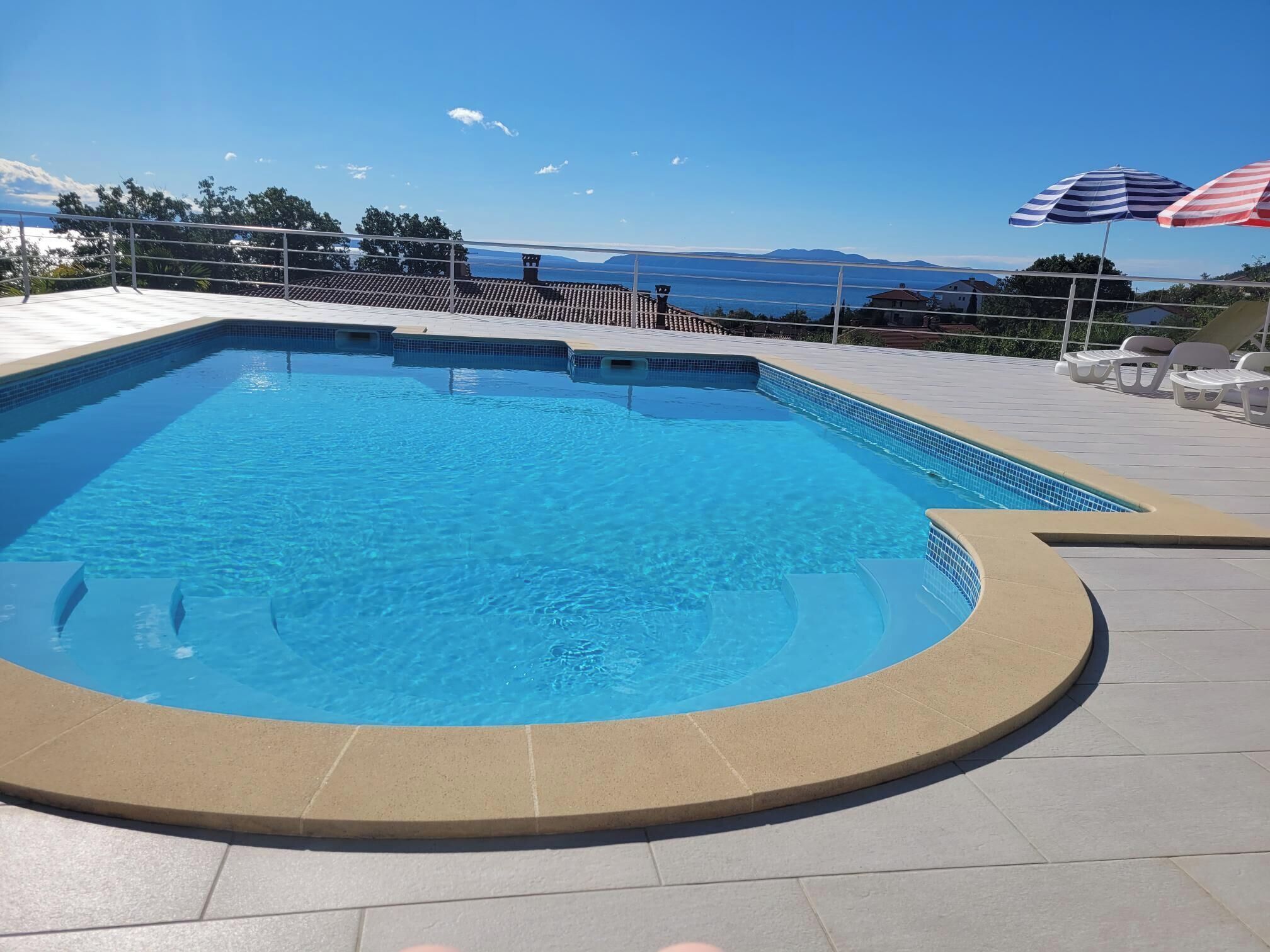 A rectangular swimming pool with a tiled deck surrounding it.