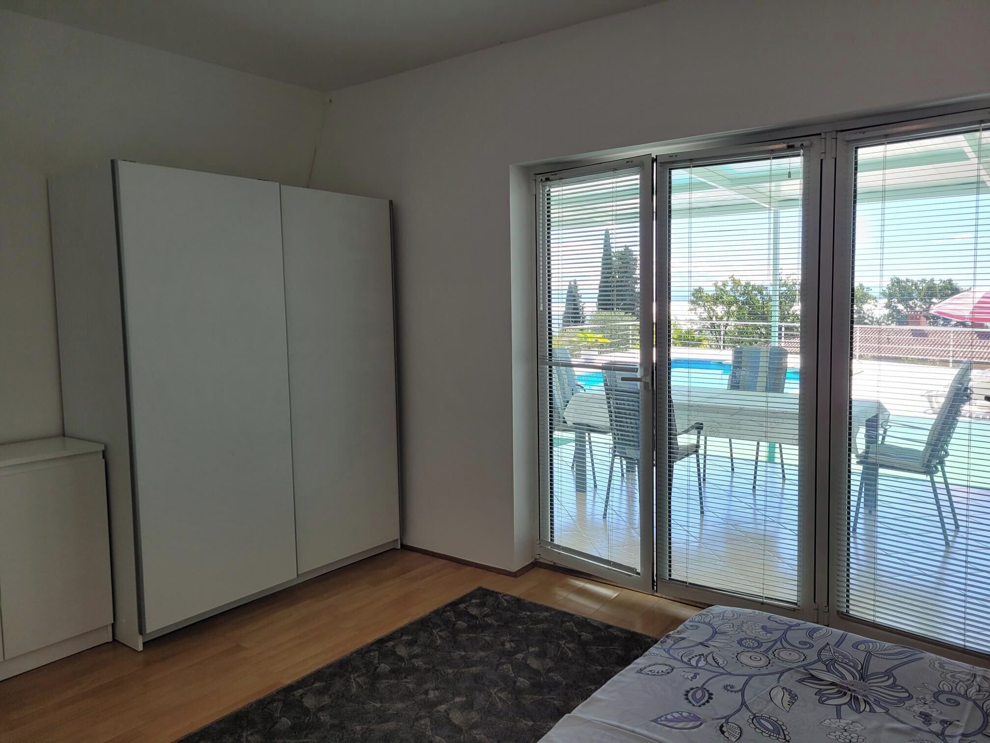A room with a sliding glass door leading to an outdoor area with a pool and chairs.