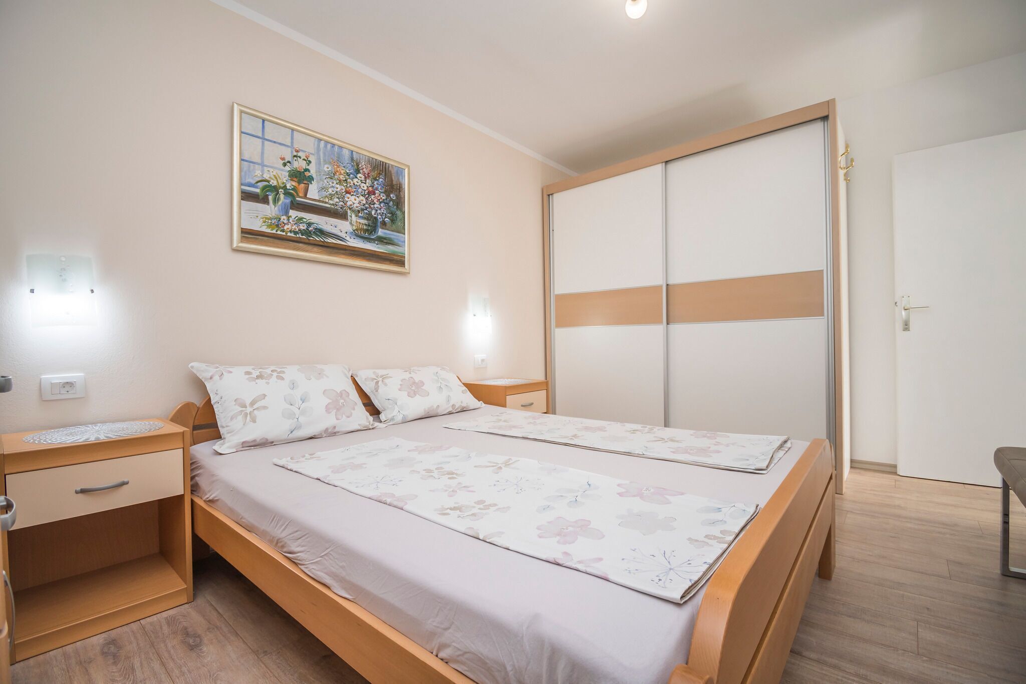Une chambre à coucher avec un lit double, une table de chevet, une commode, une armoire et un tableau au mur.