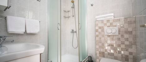 A modern bathroom with a glass-enclosed shower, a white sink, and a toilet.