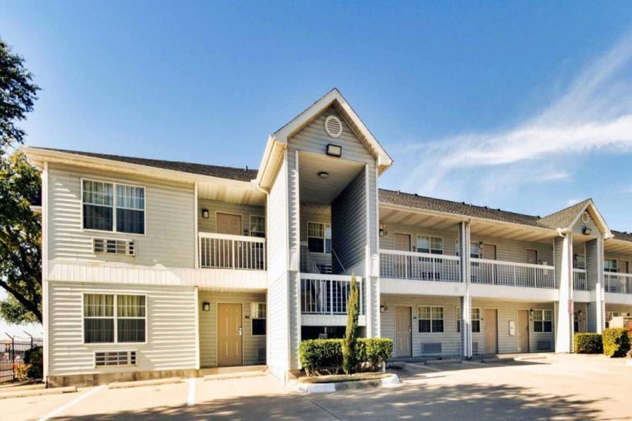 A multi-story motel with a central entrance, balconies, and a parking lot.