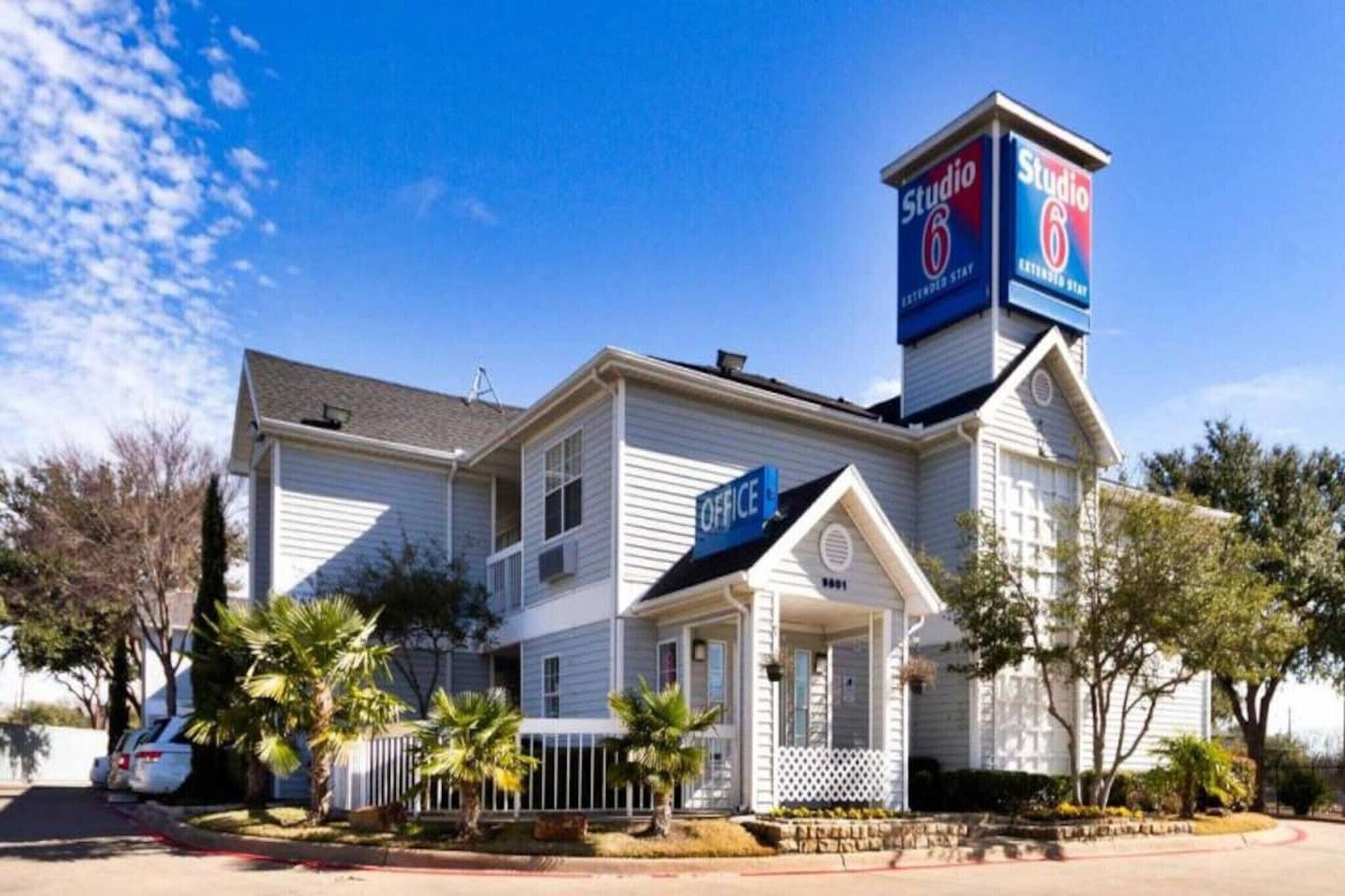 A two-story building with a prominent 'Studio 6' sign, a front office, and a small porch area.