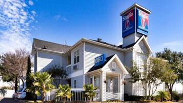 A two-story building with a prominent 'Studio 6' sign, a front office, and a small porch area.