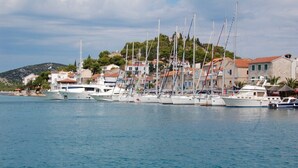 A marina with several yachts docked, a hillside with buildings, and a clear sky. - Apartments Peaceful Port (Tribunj)
