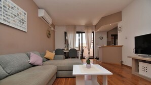 A modern living room with a grey sofa, a white coffee table, and a flat-screen TV. - Apartment Honey Bee (Pula)
