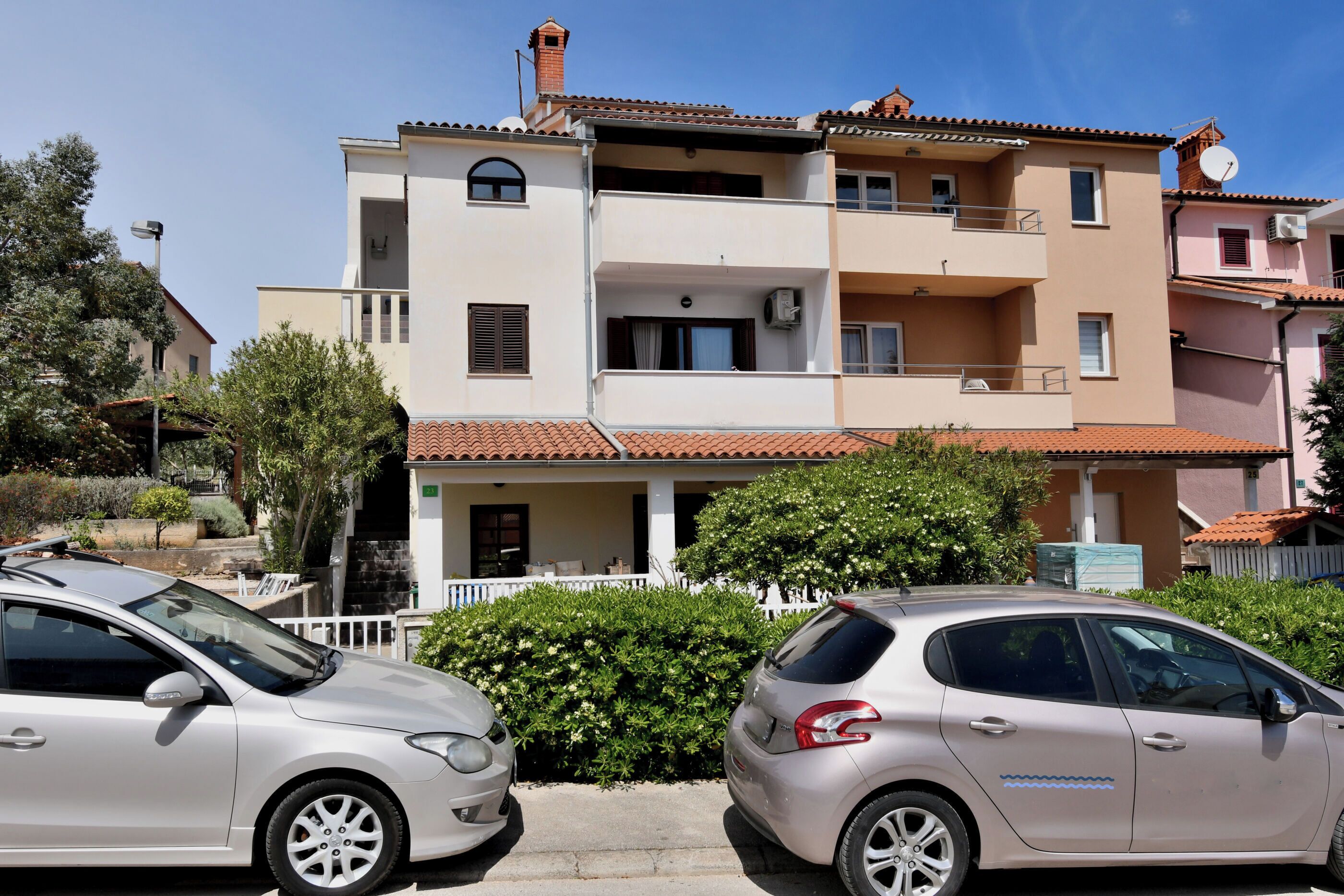 A two-story residential building with balconies, a covered porch, and a satellite dish.