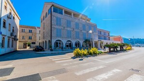 A street view with a building featuring a stone facade, arched windows, and a balcony. - Apartment Marijela (Vela Luka)