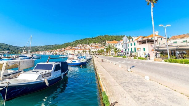A marina with boats docked, a road alongside, and buildings with shops. - Apartment Marijela (Vela Luka)