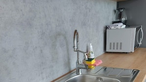 Eine moderne Küche mit Spüle aus Edelstahl, integriertem Induktionskochfeld und Mikrowelle.
