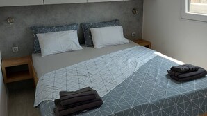 Ein Schlafzimmer mit einem Bett, zwei Nachttischen, einem Holz-Kopfteil und einem Fenster mit Blick.